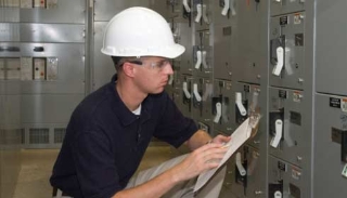An employee checking on the electrical machine and writing down what he notices, energy management, power management, field service